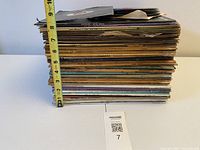 Side view of full stack of LPs and singles with tape measure showing ~8-inch height
