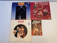Four Elvis Presley items laid out: three LP albums and one small calendar