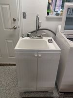 Front view of white cabinet and sink with faucet