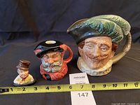 Front view of all three Royal Doulton items with tape for scale
