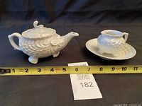 Teapot, creamer on saucer with tape for length