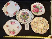 Group shot of five floral serving plates with measuring tape