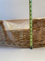 Side view of wicker dog bed showing rattan weave and vertical tape measure indicating about 9 in. height