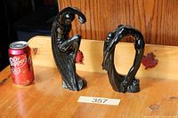 Both black glazed figurines beside soda can for scale