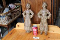 Front view of both cast iron andirons beside soda can for scale