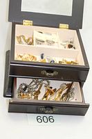 Open jewellery box top drawer showing multiple cufflinks, tie tacs, tie bars
