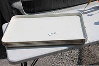 Stack of four white plastic trays on table