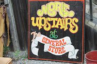 Full view of the painted wooden sign showing text and condition