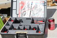 Open carry case showing compartments with Meccano parts, instruction booklet and soda can for scale