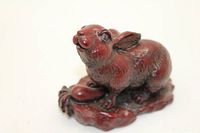 Front-left view of red resin rabbit on base