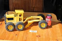 Full view of yellow Tonka grader beside soda can for scale