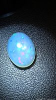 Oval cabochon opal, top view showing blue body tone and multicolored flashes
