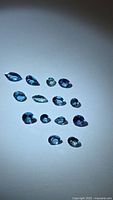 All fourteen aqua blue tanzanite stones arranged on neutral background