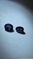 Two oval blue sapphires on neutral background