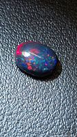 Top view of oval Ethiopian black opal showing multicolour flashes