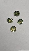 Four round yellow-green sapphires on neutral background