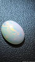 Oval cabochon fire opal on textured background