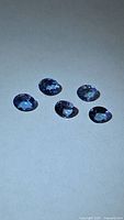 Five oval blue tanzanite stones on neutral background