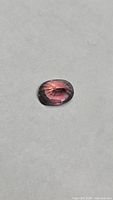 Front view of oval faceted sapphire showing pink-to-purple hue