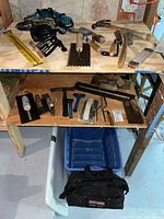 Overall view of shelves showing drills, trowels, hammers, level, clamps, and tool bag