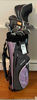 Full view of Acuity Voltage gray/lavender stand bag loaded with clubs and headcovers; DVD set visible
