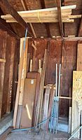 Full view of assorted lumber leaning against wall and strapped bundle overhead