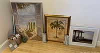 Three framed artworks and decor grouped on floor
