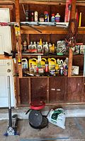 Shelving with motor oils, antifreeze jugs, aerosols, hand tools, jack handle, stool, extension cord