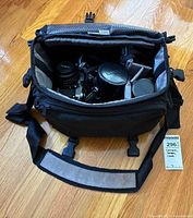 Bag opened showing camera with 50 mm lens, extra lens in case, interior dividers, exterior strap