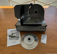 Front view of food slicer with manual, extra blade and paperwork