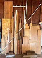 Front view of stacked plywood sheets, boards, trim pieces and poles