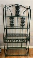 Full view of wrought iron baker’s rack with four glass shelves