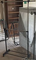 Two garment racks, fabric wardrobe closet, partial shoe rack visible