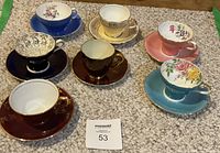 All seven teacup and saucer sets arranged on carpet