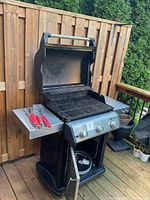 Grill open, interior grates, side shelf with utensils visible
