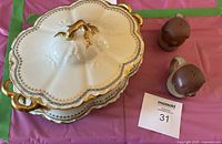 Covered dish with lid, underplate beneath, pair of animal shakers alongside