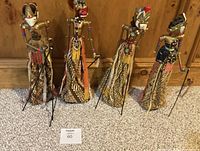 Front view of all four puppets standing, showing costumes and control rods