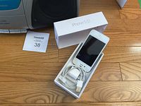 iPhone 5S with box, cable and adapter beside part of boombox