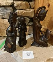 Front view of three dark hardwood figurines