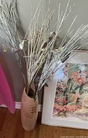 Vase with faux branches beside watercolor painting