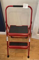 Front view of red Werner two-step folding stool extended