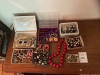 Overall view of seven containers of assorted jewellery and beads on table