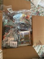 Open cardboard box showing several plastic bags each holding folded scarves