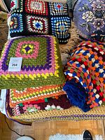 Stacked crochet afghans, pillows visible