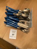 Stack of blue-handled stainless flatware pieces