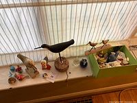 Full view of assorted bird decor on windowsill and contents of green box