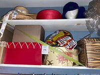 Shelf with multiple hat boxes, straw hat, red hat, purple hat on mannequin