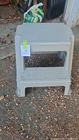 Front view of gray plastic two-step stool with lot tag visible