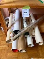 Group of rolled posters stored on shelf, showing quantity and varied roll colors