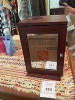 Front view of wood jewelry cabinet with mirrored door and knob